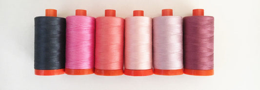Colorful spools of Aurifil cotton thread lined up, ready for your next quilting or piecing project.